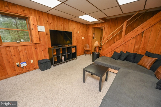 living room with carpet flooring, a drop ceiling, and wooden walls