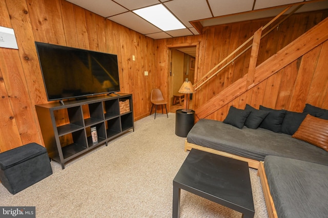 living room featuring a paneled ceiling, carpet flooring, and wood walls