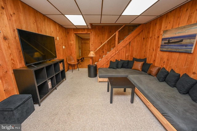 living room featuring carpet flooring, a paneled ceiling, and wood walls