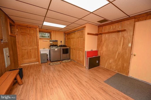 kitchen featuring a paneled ceiling, wood walls, washer and clothes dryer, and light hardwood / wood-style floors