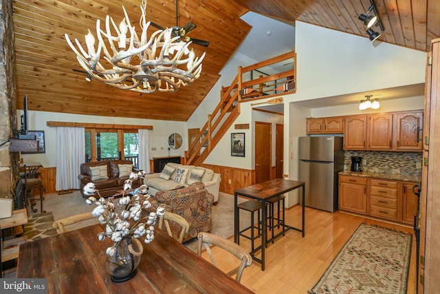 living room featuring rail lighting, light hardwood / wood-style flooring, high vaulted ceiling, a notable chandelier, and wood ceiling