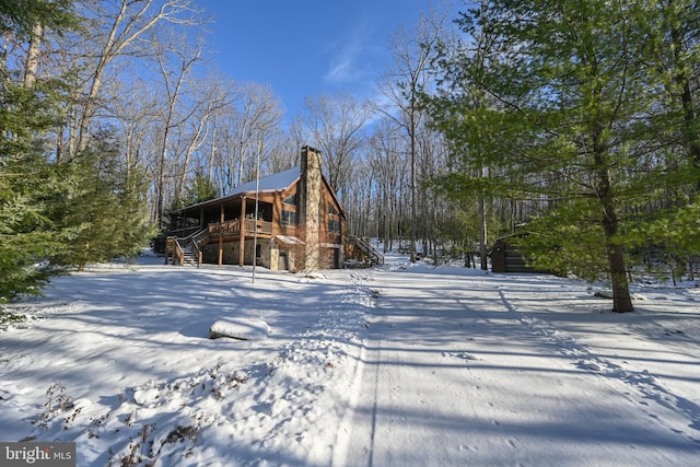 snow covered back of property featuring a wooden deck