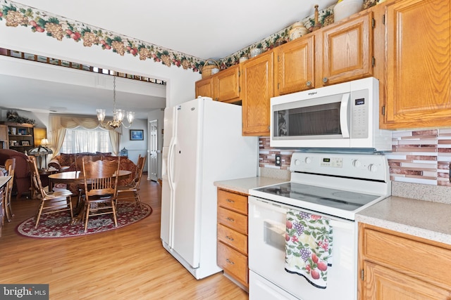 kitchen with decorative backsplash, a notable chandelier, white appliances, and light wood-type flooring