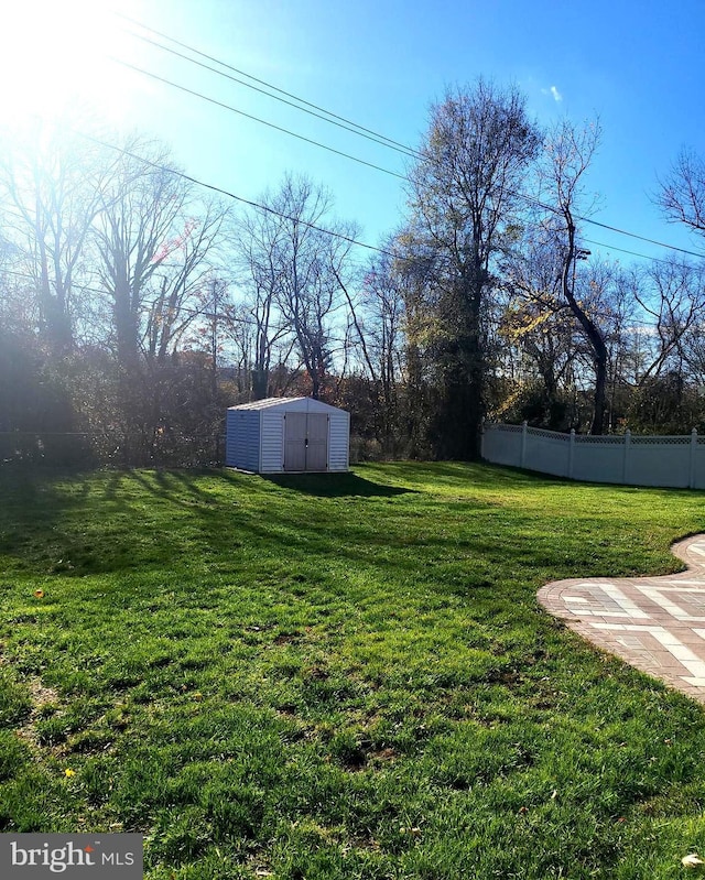 view of yard featuring an outdoor structure, fence, and a storage unit