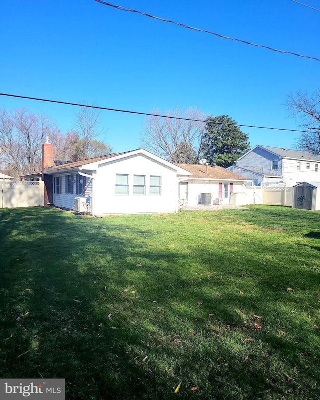 back of house with a yard, central AC, a chimney, and fence