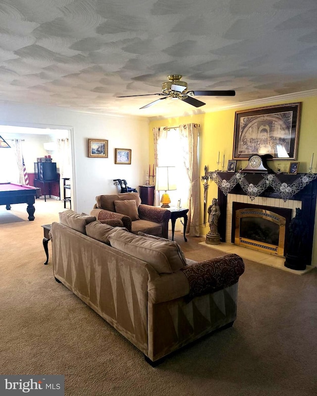 carpeted living room with crown molding, a fireplace, a textured ceiling, and ceiling fan