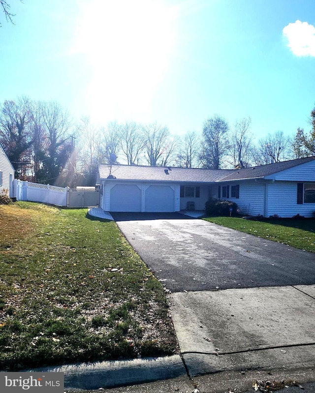 view of front of house with a front yard, driveway, an attached garage, and fence