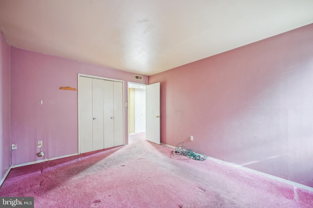 unfurnished bedroom featuring light carpet and a closet