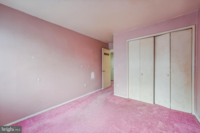 unfurnished bedroom with light colored carpet and a closet