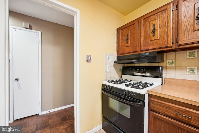 kitchen featuring dark parquet flooring, backsplash, and gas range gas stove