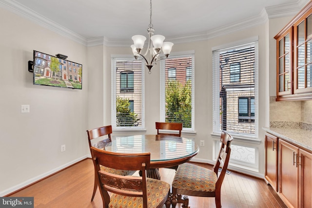 dining room with a wealth of natural light, crown molding, a chandelier, and light wood-type flooring