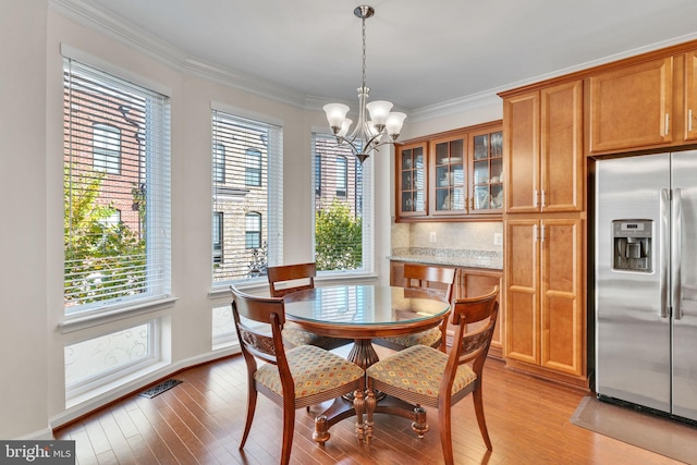 dining area featuring crown molding, an inviting chandelier, and light wood-type flooring