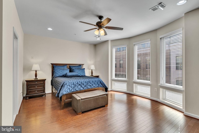 bedroom featuring hardwood / wood-style flooring, ceiling fan, and multiple windows