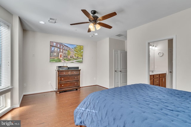 bedroom featuring wood-type flooring, ensuite bath, ceiling fan, and sink