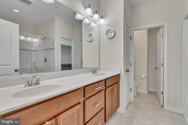 bathroom featuring tile patterned flooring, vanity, toilet, and an enclosed shower