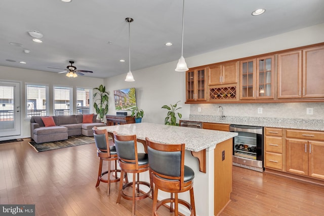 kitchen with a kitchen breakfast bar, a center island, decorative light fixtures, and beverage cooler