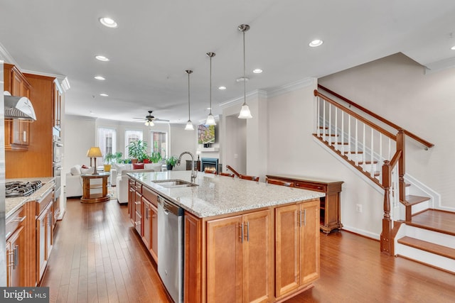 kitchen with hanging light fixtures, crown molding, sink, an island with sink, and appliances with stainless steel finishes