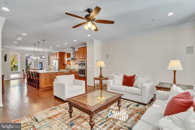 living room with light hardwood / wood-style flooring, ceiling fan, and crown molding