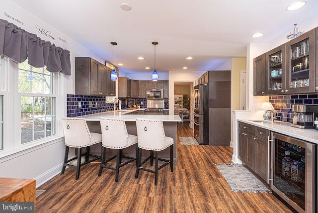 kitchen featuring sink, stainless steel appliances, beverage cooler, dark hardwood / wood-style flooring, and kitchen peninsula