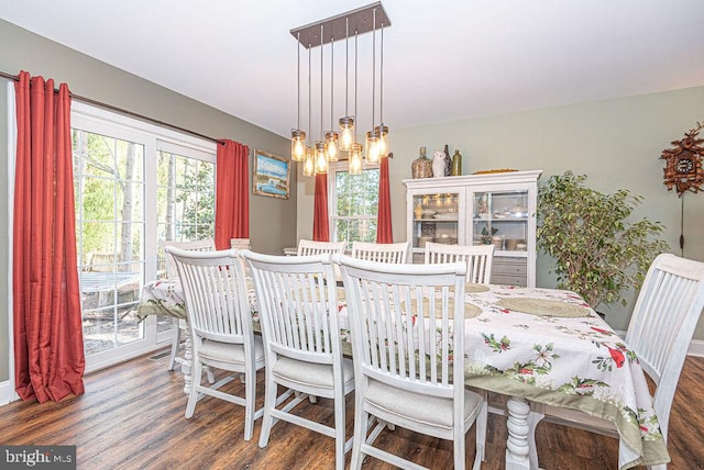 dining area featuring a chandelier, dark wood-type flooring, and a healthy amount of sunlight