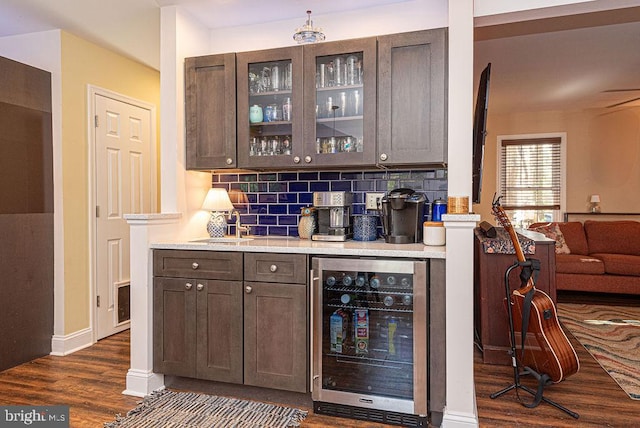 bar featuring decorative backsplash, dark brown cabinetry, dark hardwood / wood-style floors, and wine cooler