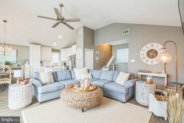 living room featuring sink, ceiling fan with notable chandelier, light hardwood / wood-style floors, and lofted ceiling