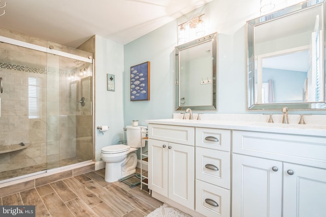 bathroom with a shower with door, vanity, and toilet