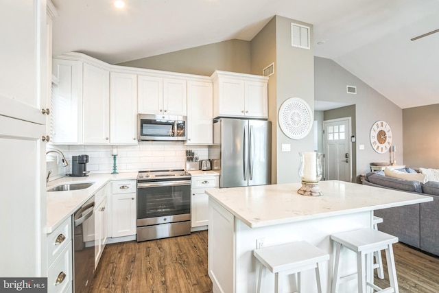 kitchen with stainless steel appliances, dark wood-type flooring, sink, white cabinets, and a kitchen island