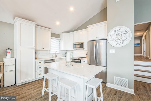 kitchen with a center island, sink, dark hardwood / wood-style floors, appliances with stainless steel finishes, and white cabinetry