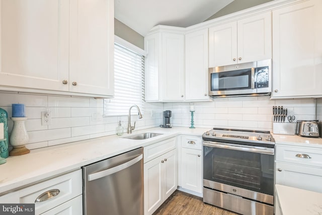 kitchen with appliances with stainless steel finishes, backsplash, sink, light hardwood / wood-style floors, and white cabinetry