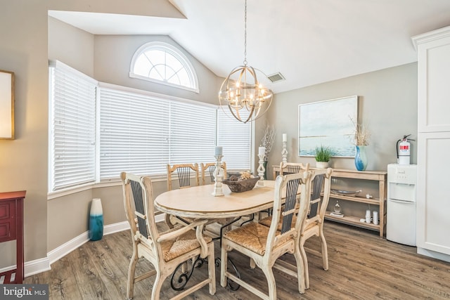 dining area with wood-type flooring, vaulted ceiling, and a notable chandelier