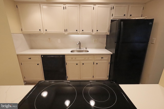 kitchen with black appliances, backsplash, white cabinetry, and sink