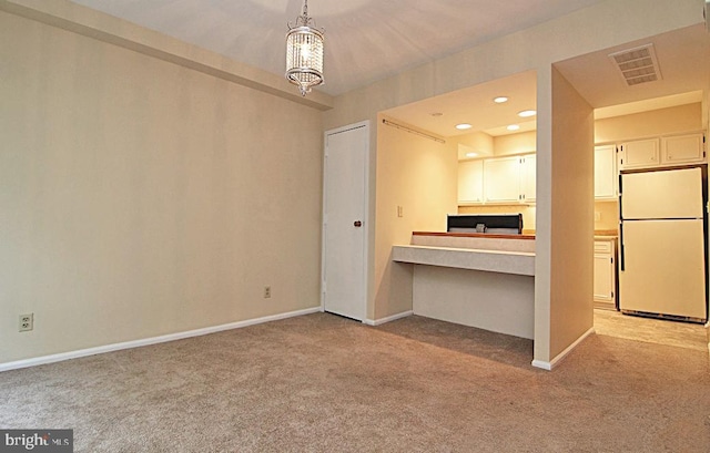 kitchen featuring light colored carpet, pendant lighting, an inviting chandelier, white fridge, and white cabinetry