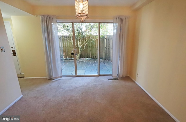 empty room featuring carpet floors and an inviting chandelier