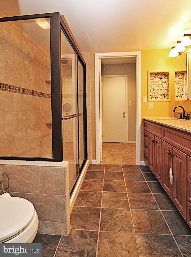 bathroom with vanity, toilet, and a shower with door