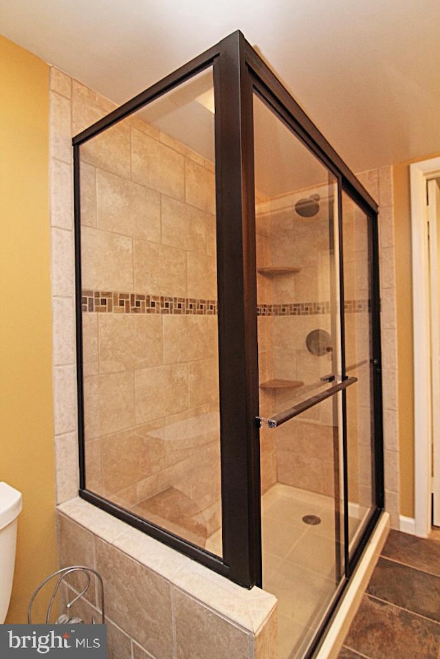 bathroom featuring tile patterned flooring, toilet, and an enclosed shower