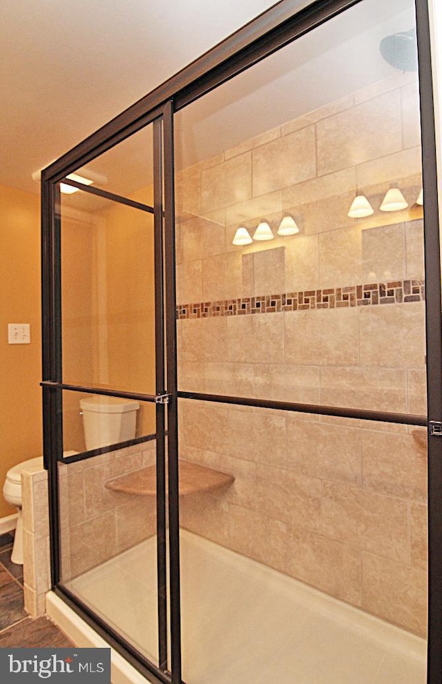 bathroom featuring a shower with shower door and toilet