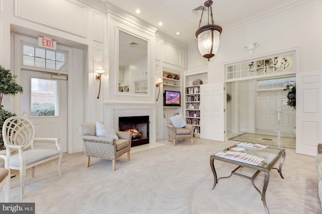 carpeted living room with a high ceiling, ornamental molding, built in features, and a fireplace