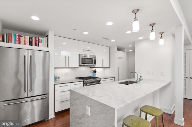 kitchen with pendant lighting, sink, white cabinetry, high quality appliances, and kitchen peninsula