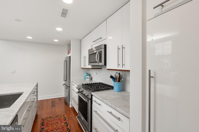 kitchen featuring white cabinetry, backsplash, dark hardwood / wood-style floors, light stone counters, and premium appliances