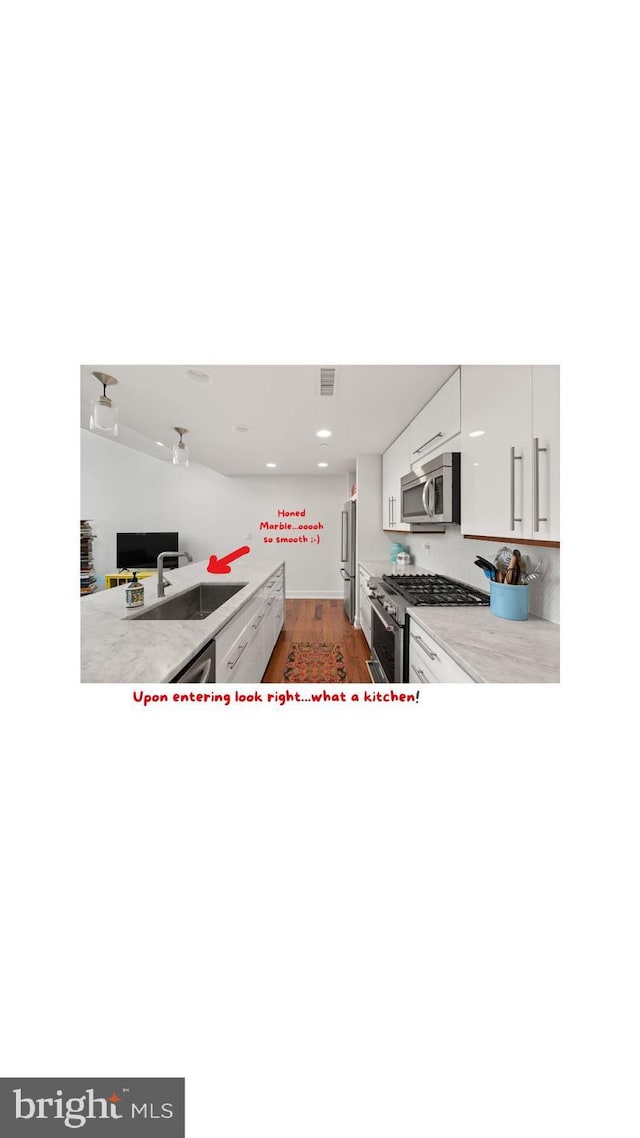 kitchen featuring dark wood-type flooring, sink, white cabinets, stainless steel appliances, and backsplash