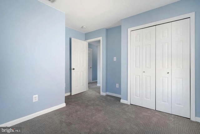 unfurnished bedroom with dark carpet and a closet