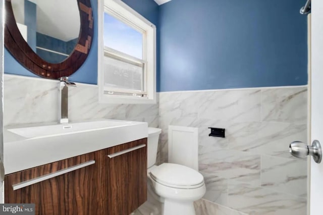 bathroom with vanity, toilet, and tile walls