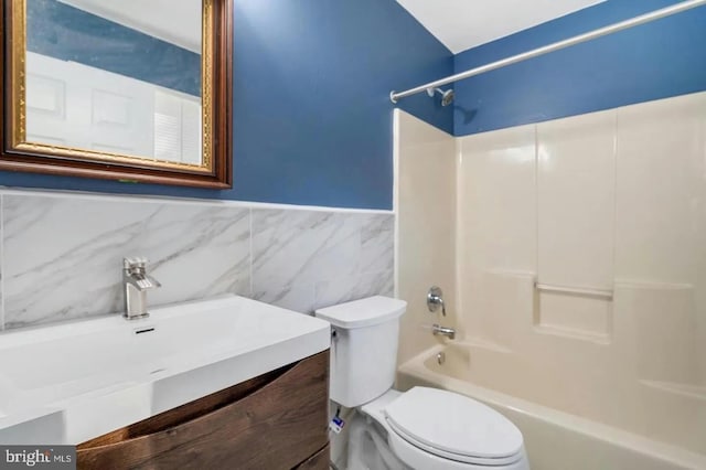 full bathroom featuring vanity, bathtub / shower combination, tile walls, and toilet