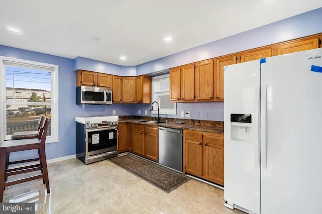 2396 Elvans Rd SE, Washington, DC 20020 - kitchen with stainless steel appliances, dark countertops, brown cabinets, a sink, and baseboards