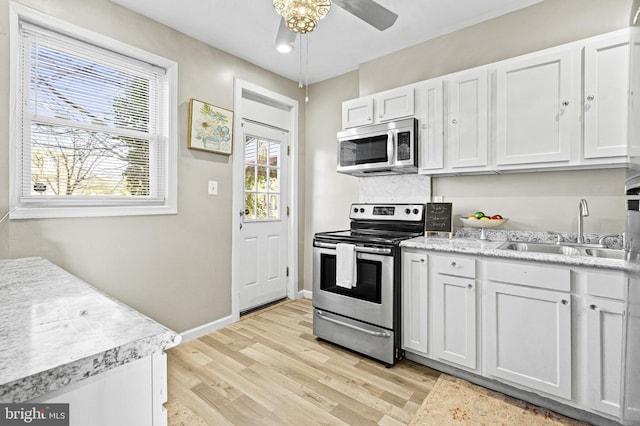 kitchen featuring ceiling fan, sink, light hardwood / wood-style flooring, white cabinets, and appliances with stainless steel finishes