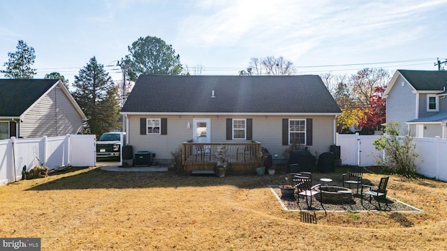 back of house featuring a lawn, a wooden deck, central air condition unit, and a fire pit