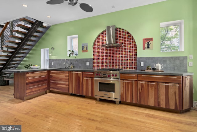 kitchen with wall chimney exhaust hood, sink, designer stove, and light wood-type flooring