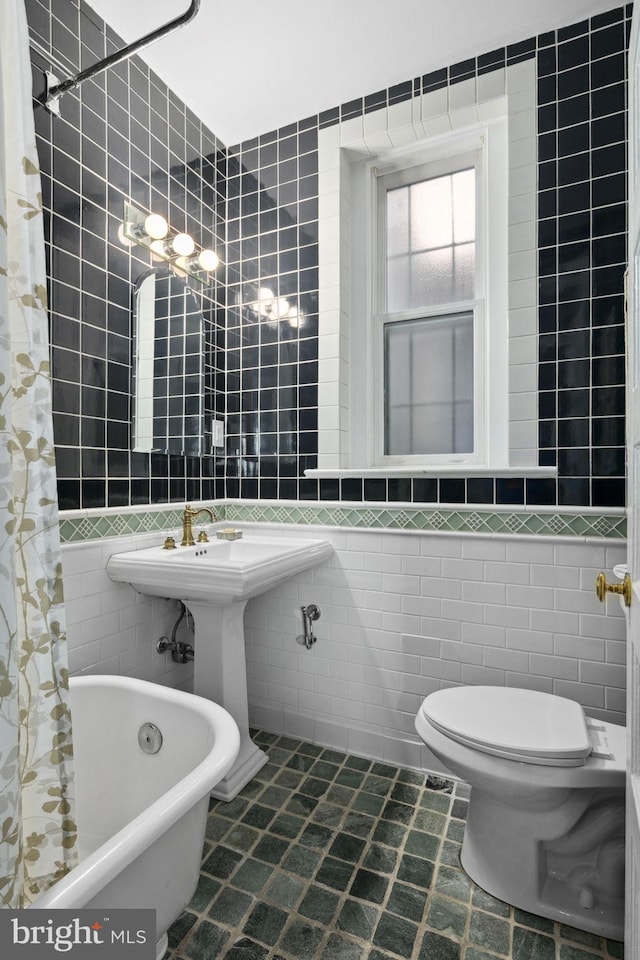 bathroom featuring tile patterned floors, toilet, shower / bath combo with shower curtain, and tile walls