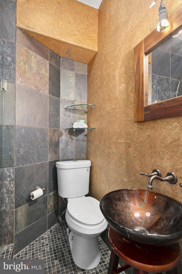 bathroom with tile patterned flooring, toilet, tile walls, and sink